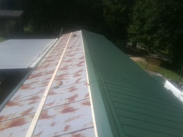 Old rusted panels beside newly installed green metal roofing — Wind Damage Roof Repair by Roofing Brothers in Perry